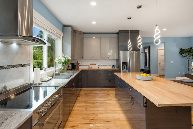 a view of a kitchen with kitchen island a large counter top space a sink a counter space and stainless steel appliances