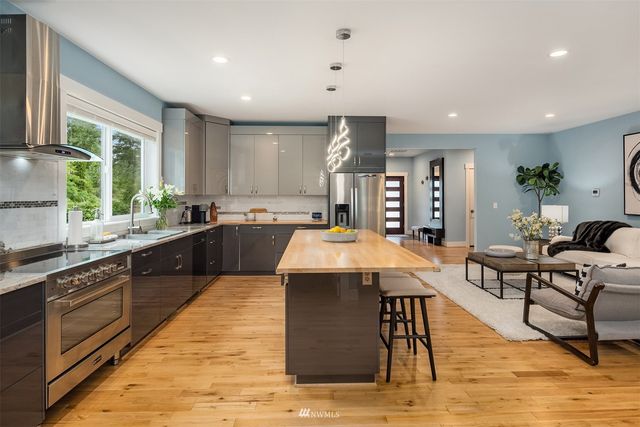 a large kitchen with kitchen island a large counter top space a sink stainless steel appliances and cabinets