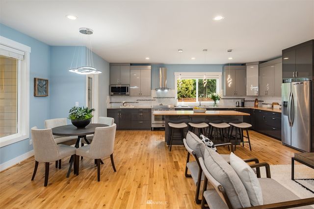 a kitchen with stainless steel appliances granite countertop table chairs stove a refrigerator and cabinets