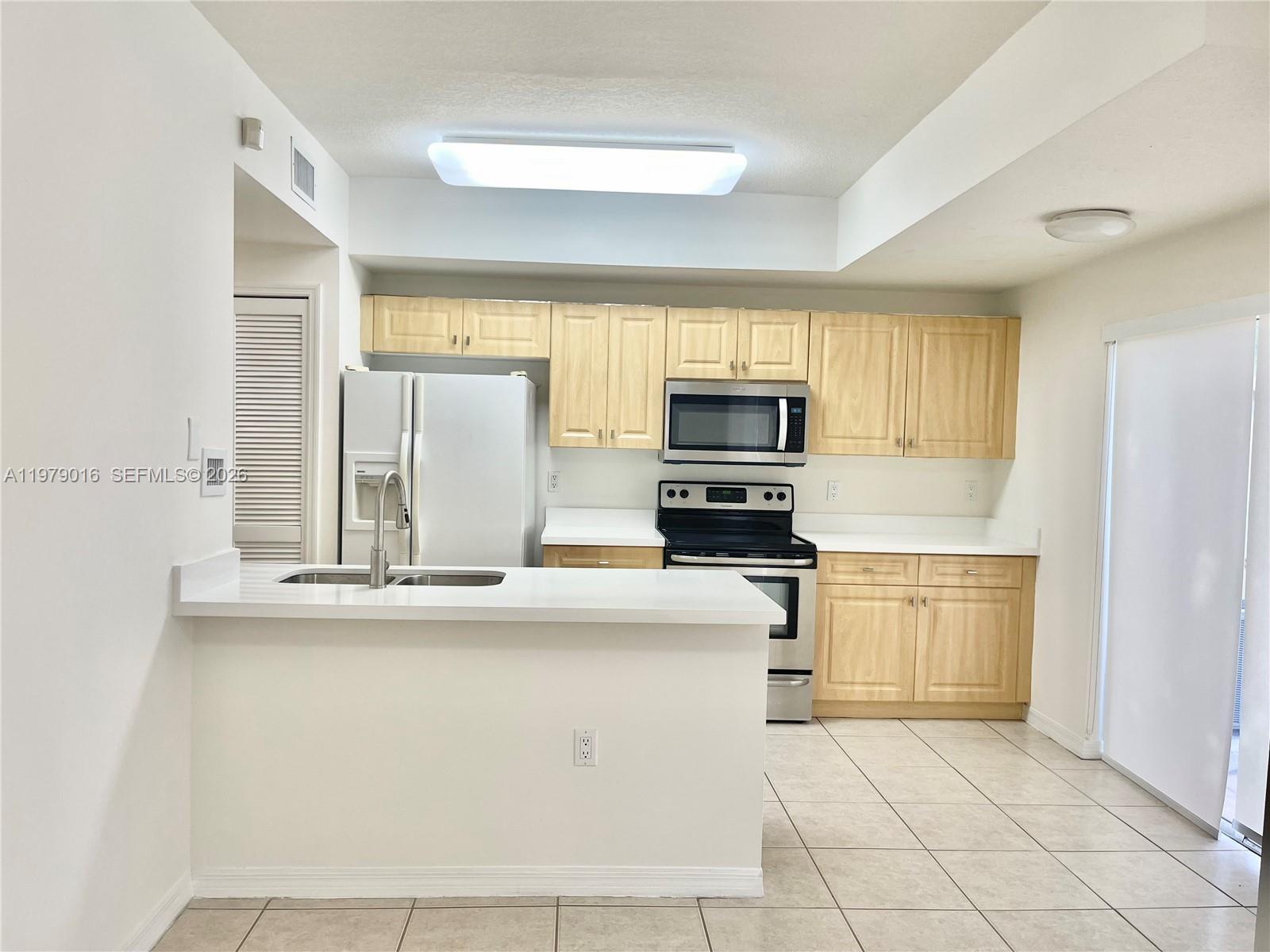10160 Southwest 88th Street, Unit 201 Miami, FL 33176 - Photo 15 of 43 a kitchen with stainless steel appliances a sink a stove a microwave a refrigerator a counter top space and cabinets