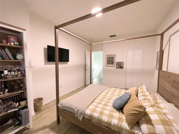 a bedroom with a large bed and a flat tv screen