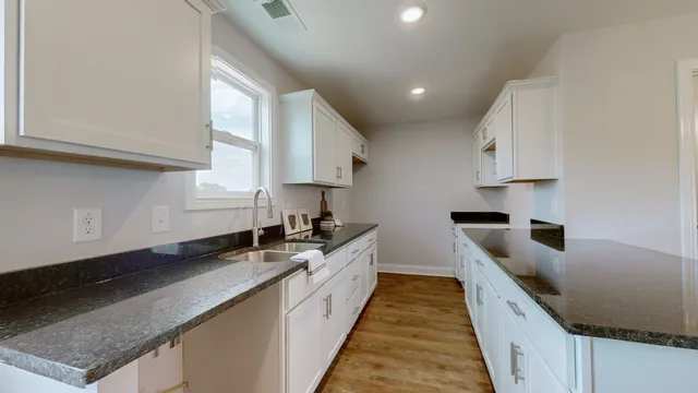 a kitchen with granite countertop a sink a stove and a wooden cabinets