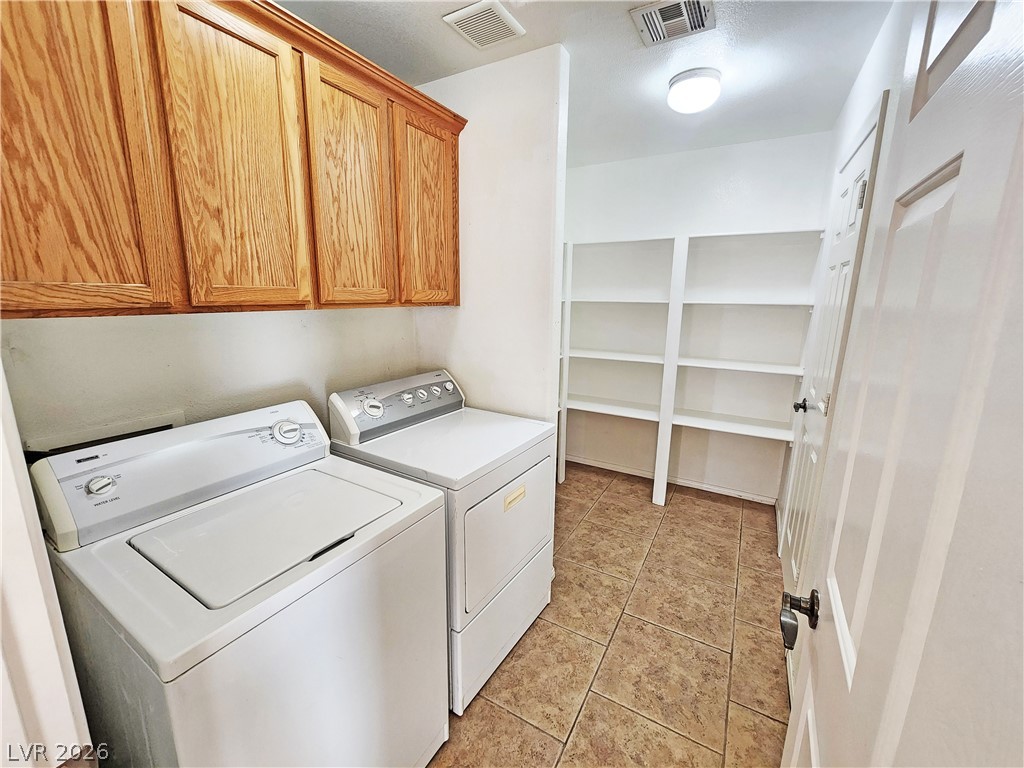 3680 Ravine Avenue Pahrump, NV 89048 - Photo 11 of 28 Clothes washing area featuring washing machine and dryer, visible vents, light tile patterned floors, and cabinet space