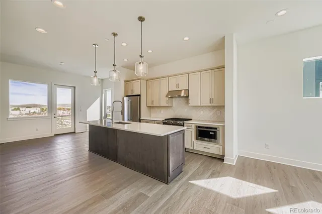 a large kitchen with stainless steel appliances granite countertop a stove and a wooden floors