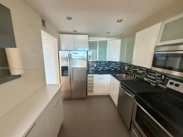 a kitchen with stainless steel appliances granite countertop a refrigerator and a stove top oven