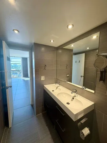 a bathroom with a sink double vanity granite tub shower and a mirror