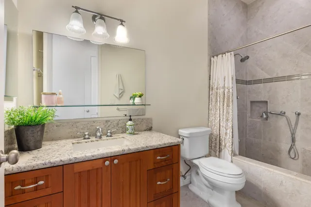 a bathroom with a granite countertop sink toilet a large mirror a shower and a bathtub