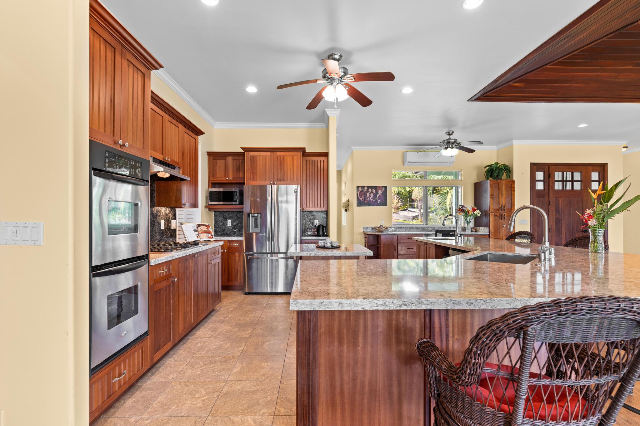 28-256 Akaka Falls Road Honomu, HI 96728 - Photo 5 of 30 a kitchen with stainless steel appliances granite countertop a refrigerator a sink dishwasher a stove and a dining table with wooden floor
