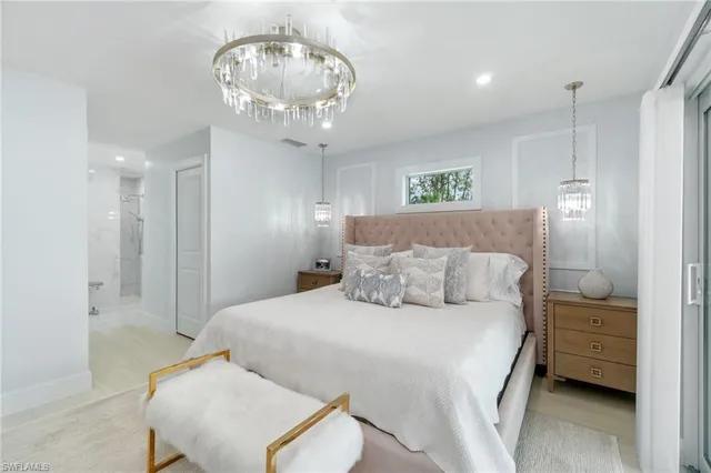 a spacious bedroom with a bed a chandelier and a mirror