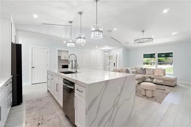 a large kitchen with kitchen island a large counter space a sink appliances and living room view