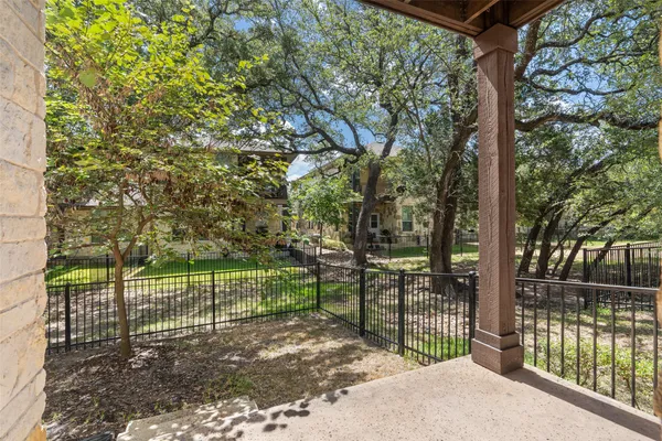 a view of a backyard with large trees and wooden fence