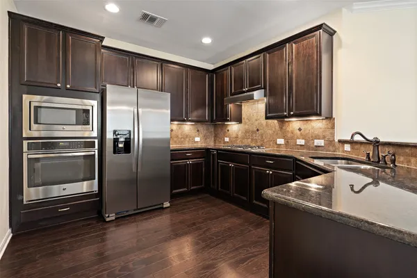 a kitchen with kitchen island granite countertop wooden cabinets a refrigerator and a sink