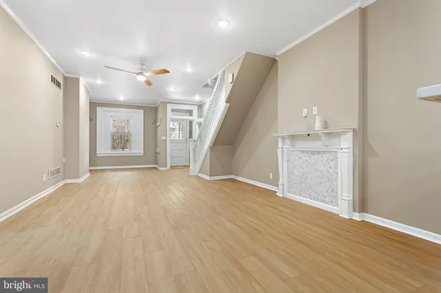 a view of empty room with wooden floor and fan