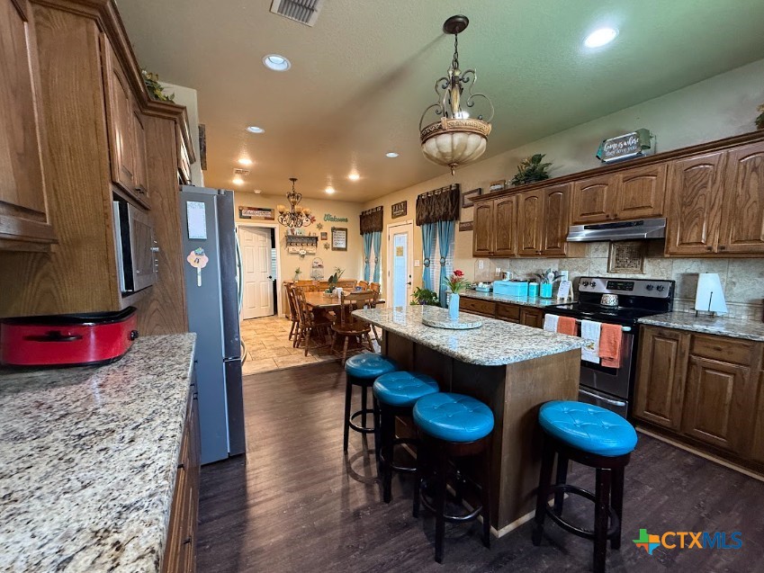 609 Highway 123 Stockdale, TX 78160 - Photo 10 of 26 a kitchen with stainless steel appliances granite countertop a table chairs and a refrigerator
