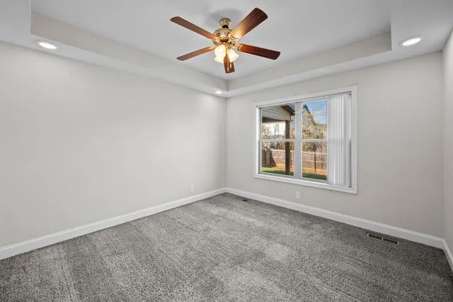 an empty room with window and ceiling fan