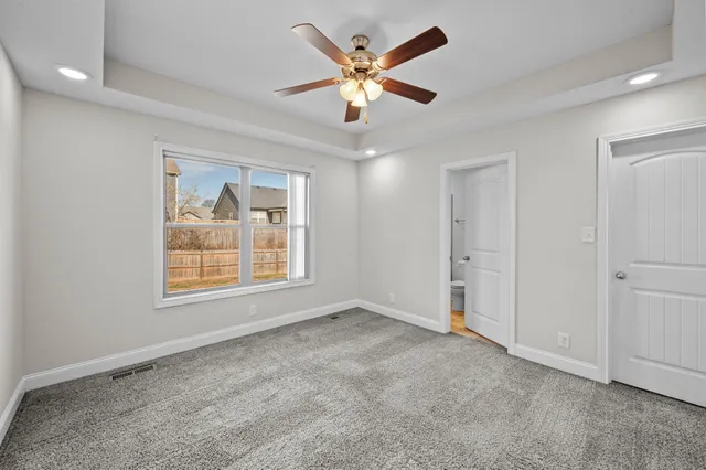 an empty room with ceiling fan and window