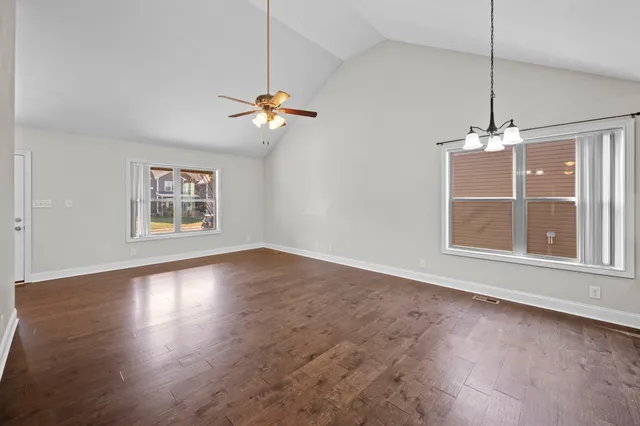 an empty room with windows and ceiling fan