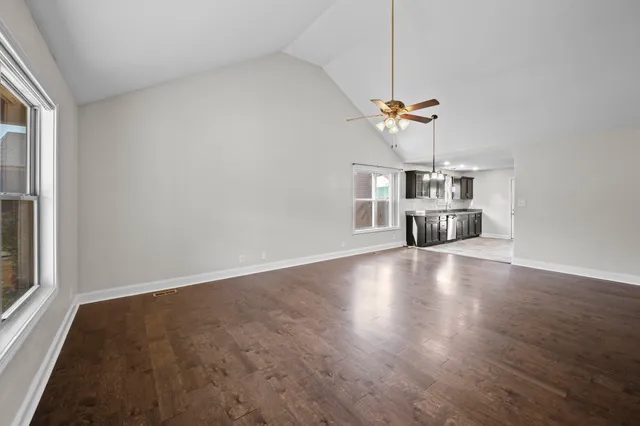 a view of empty room with wooden floor and ceiling fan