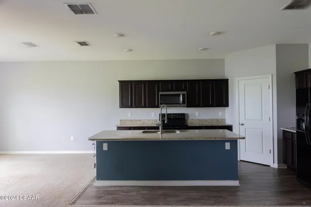 a kitchen with kitchen island stainless steel appliances a sink and a refrigerator