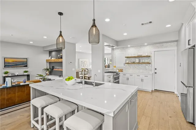 a kitchen with stainless steel appliances kitchen island granite countertop a sink a stove a refrigerator and island with wooden floor