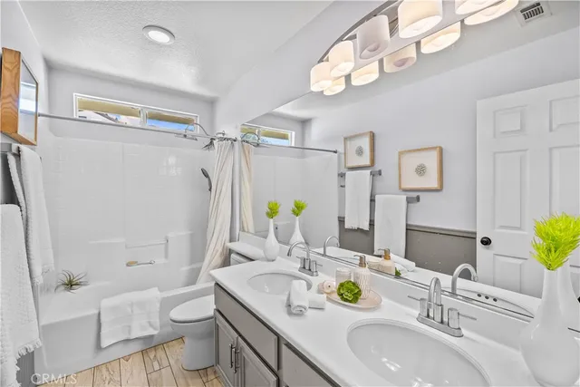a bathroom with a granite countertop double vanity sink toilet and a mirror