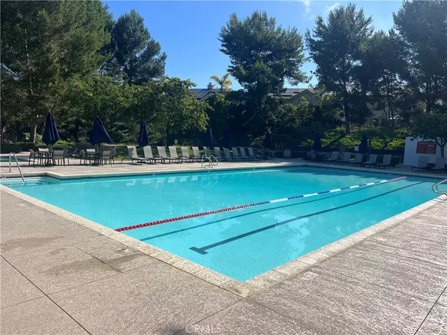 a view of a swimming pool with a bench and trees around