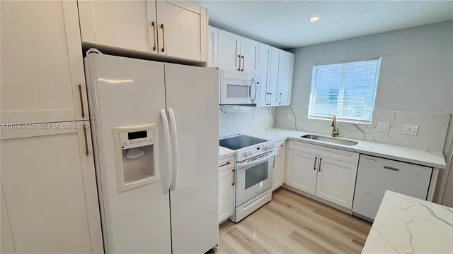 a kitchen with stainless steel appliances granite countertop a refrigerator sink and white cabinets