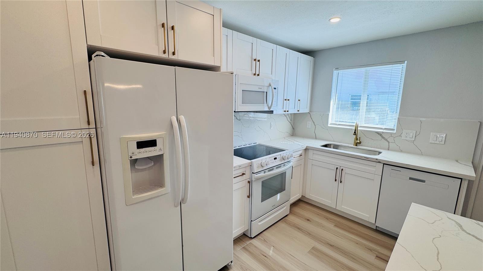 808 Northeast 2nd Street, Unit A Hallandale Beach, FL 33009 - Photo 4 of 11 a kitchen with stainless steel appliances granite countertop a refrigerator sink and white cabinets