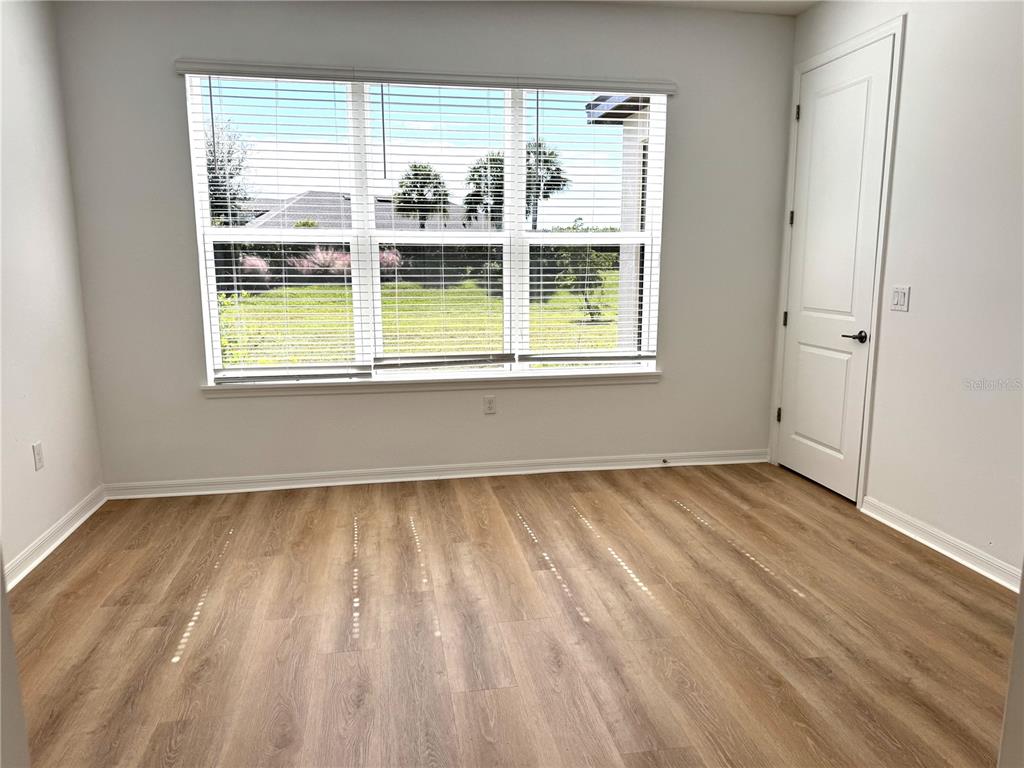 7775 Nightfall Terrace Sarasota, FL 34241 - Photo 8 of 36 an empty room with wooden floor and windows