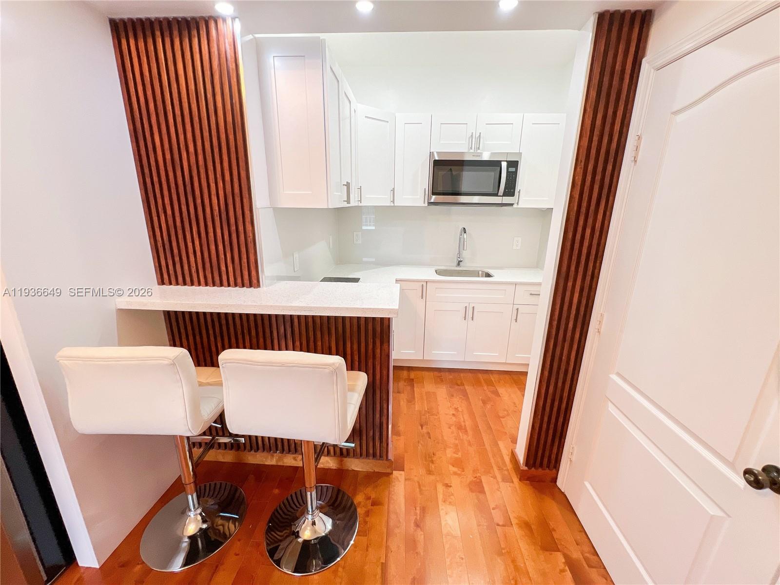 3884 Southwest 150th Court Miami, FL 33185 - Photo 28 of 45 a kitchen with a sink a stove a microwave a refrigerator and white cabinets