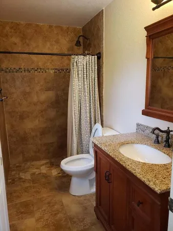 a bathroom with a granite countertop sink toilet and shower