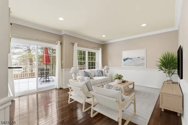 a living room with furniture a large window wooden floor and a rug