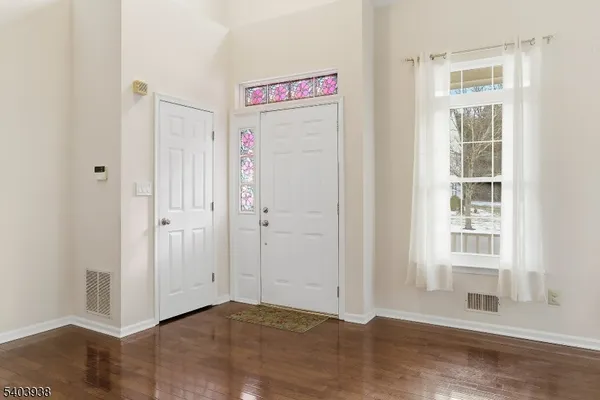 a view of an empty room with wooden floor and windows