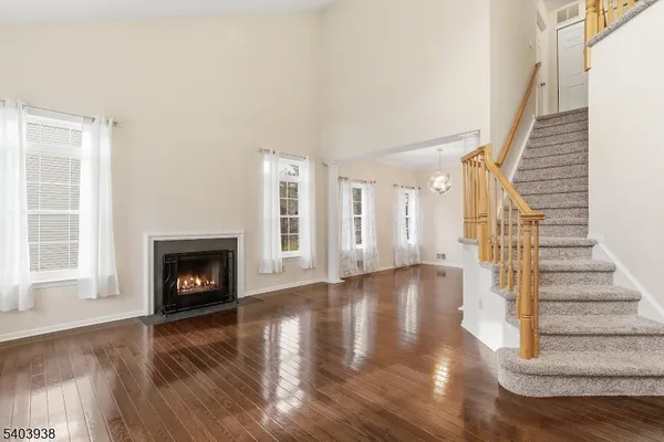 a view of an empty room with wooden floor fireplace and a window