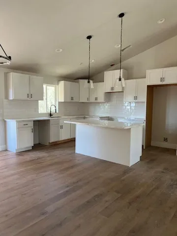 a large kitchen with kitchen island white cabinets and stainless steel appliances