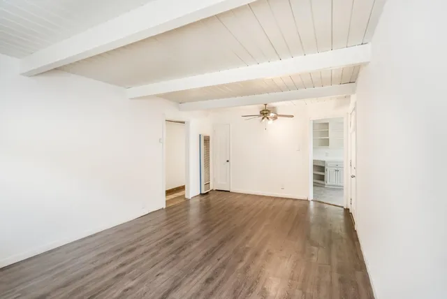 an empty room with wooden floor and a ceiling fan