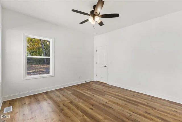 an empty room with a window and a fan