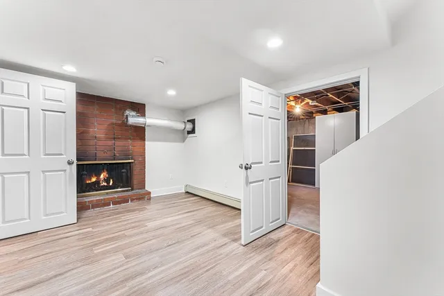 an empty room with wooden floor fireplace and windows