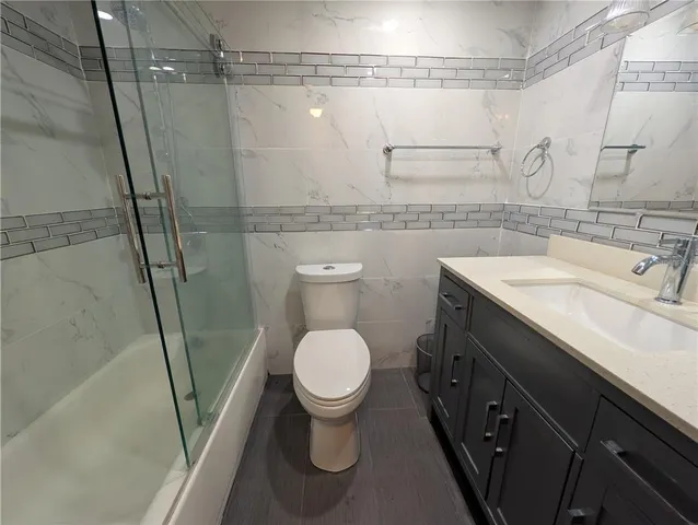 a bathroom with a granite countertop sink toilet and shower