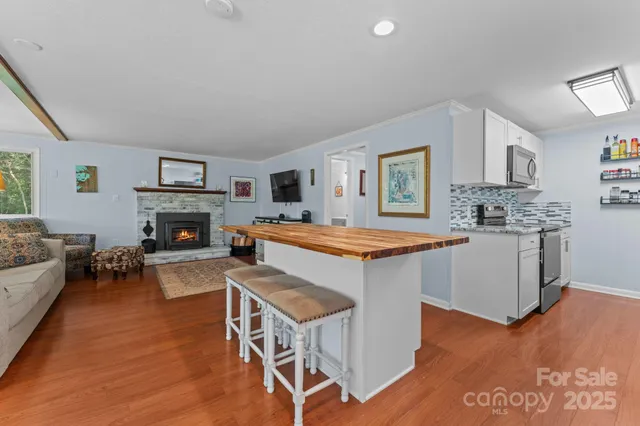 a kitchen with granite countertop a stove top oven a sink dishwasher and a fireplace with wooden floor