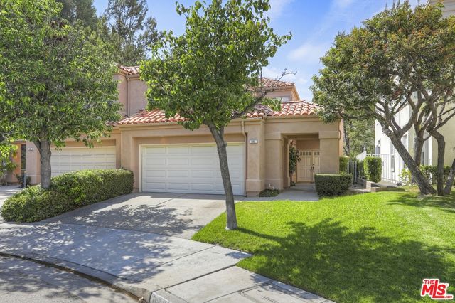 a front view of a house with a yard and an trees