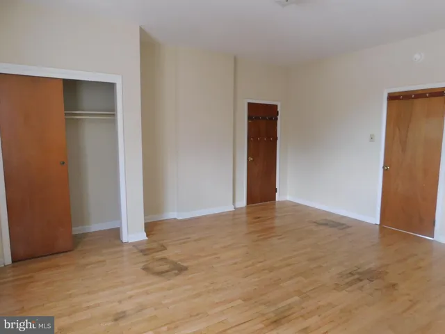 a view of an empty room with wooden floor and closet