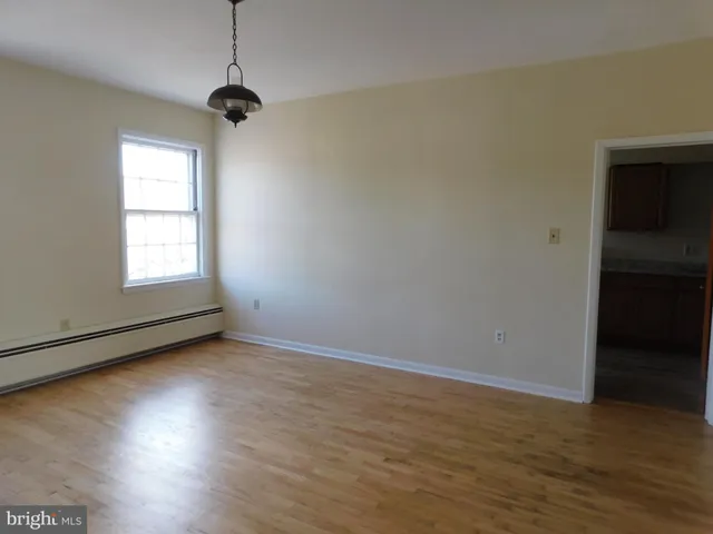 an empty room with wooden floor cabinet and windows