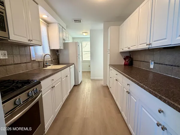 a kitchen with granite countertop a sink stove and cabinets
