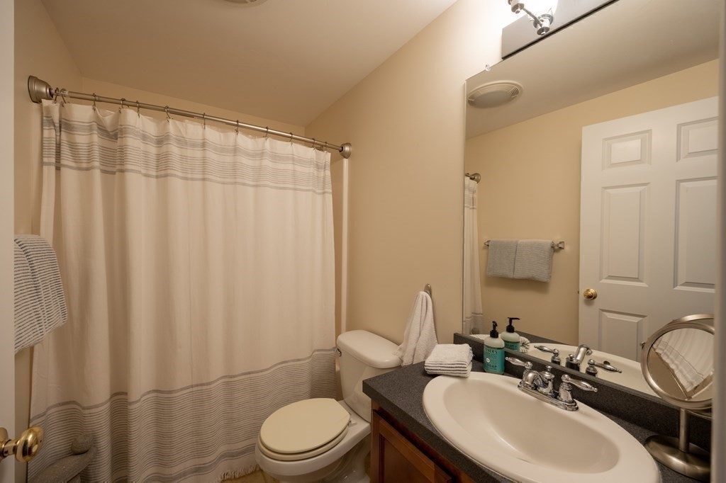 3 Harbor Mist Drive, Unit 3 Fairhaven, MA 02719 - Photo 21 of 28 a bathroom with a sink a toilet a mirror and shower curtain