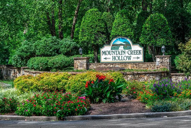 a view of a sign board with flower plants and wooden fence