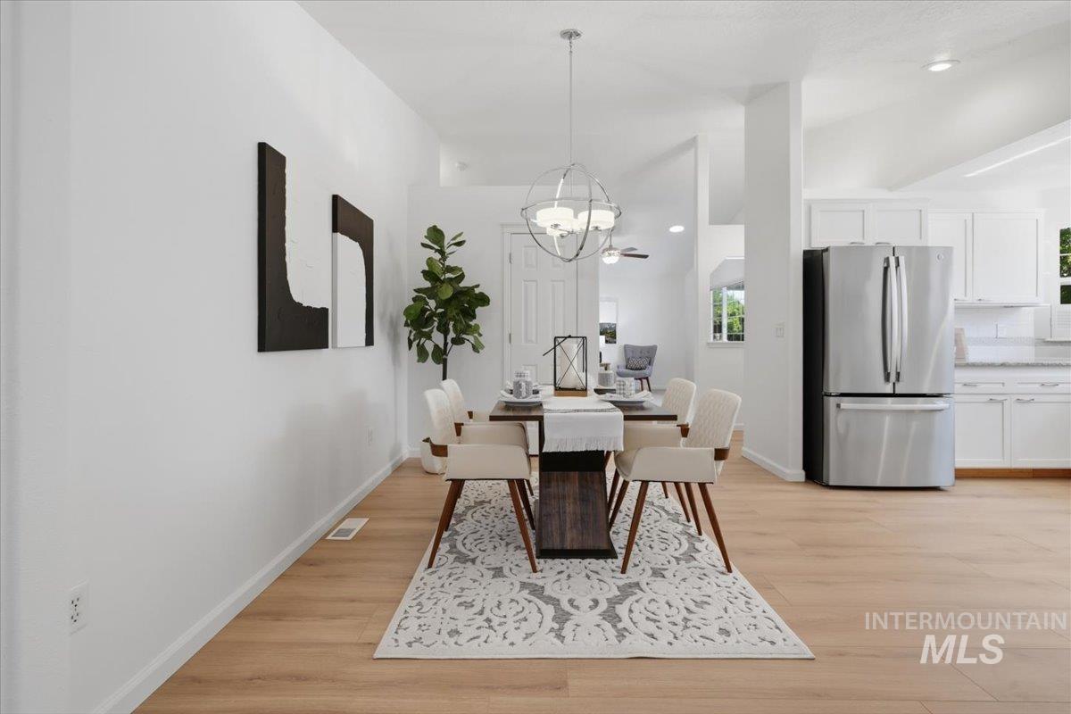 2075 North Springland Place Boise, ID 83713 - Photo 10 of 49 Open-concept living space featuring wood-finish flooring, a contemporary chandelier, white cabinetry, and stainless steel appliances