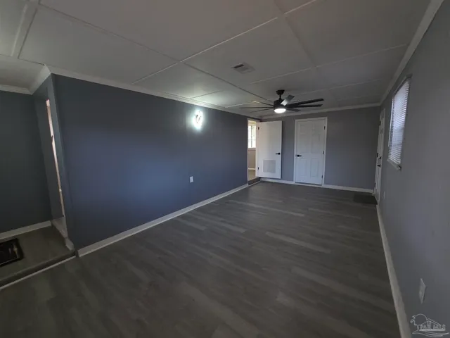 an empty room with wooden floor and a ceiling fan