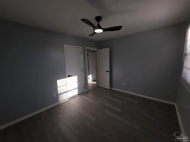 a view of empty room with wooden floor and fan