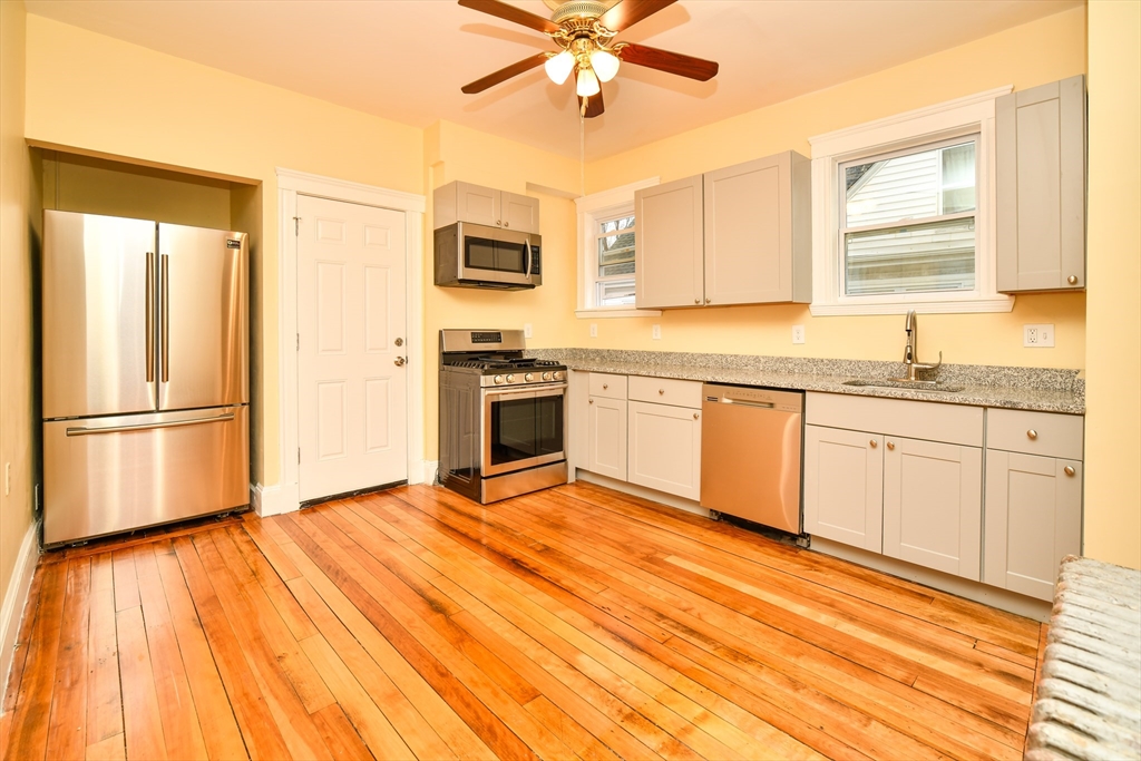 15 Vesta Road, Unit 3 Boston, MA 02124 - Photo 1 of 1 a kitchen with stainless steel appliances granite countertop a stove a sink dishwasher and a refrigerator with wooden floor